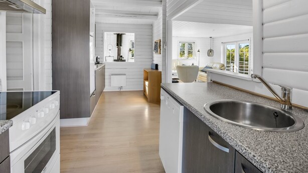 A modern kitchen with white cabinetry, a granite countertop, and a stainless steel sink.