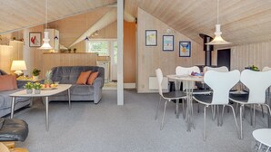A cozy, well-lit room with a grey sofa, a dining table with white chairs, and a kitchen area in the background. - "Runulf" - 2.9km from the sea by Interhome (Rømø)
