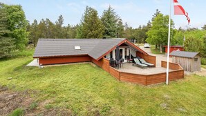 A cabin with a sloped roof, a deck with lounge chairs, and a flagpole. - "Runulf" - 2.9km from the sea by Interhome (Rømø)