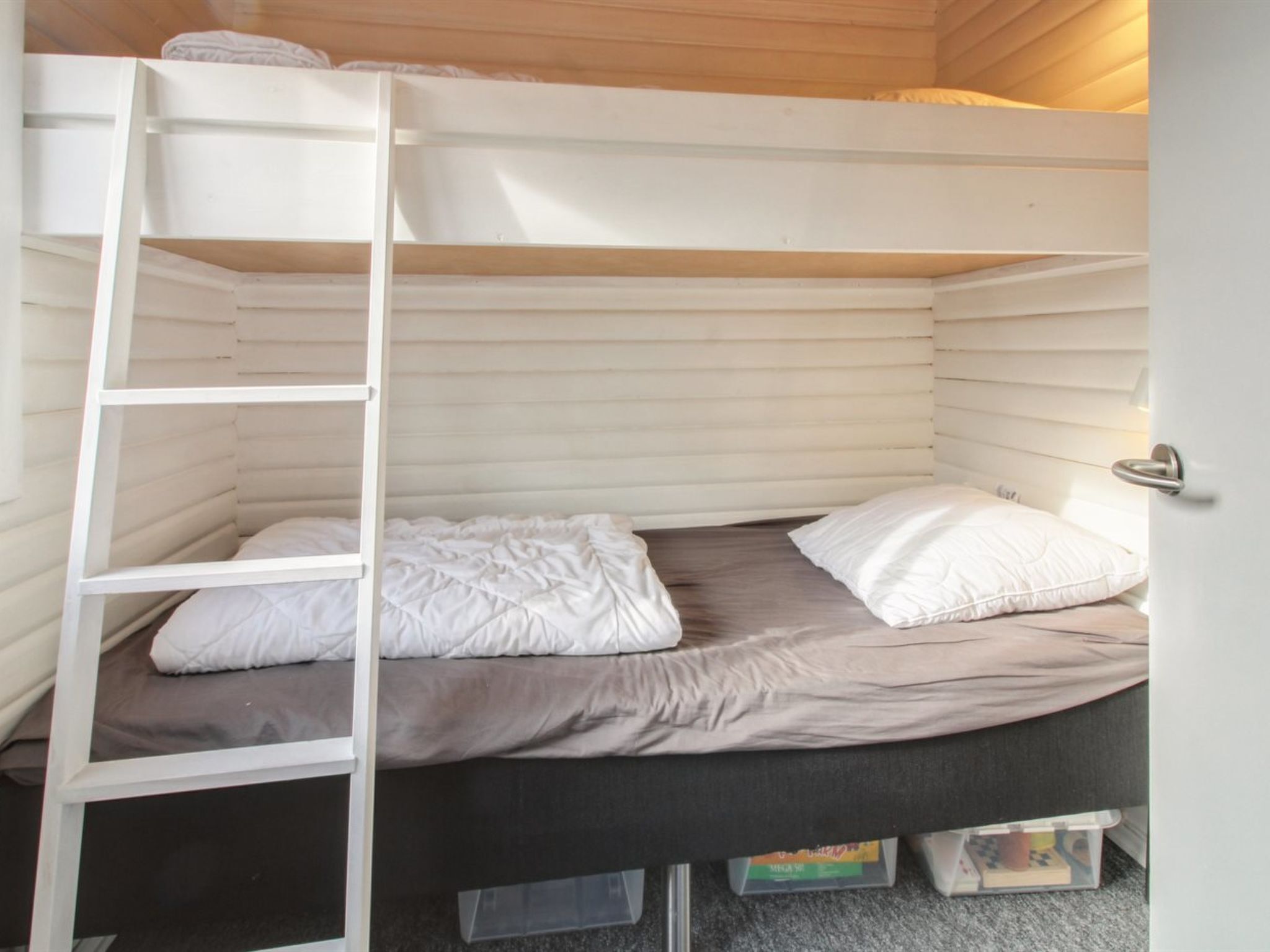 A bunk bed with a ladder, a gray mattress, and white pillows.