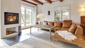 A modern living room with a fireplace, leather sofa, and wooden flooring. - "Risto" - 2.3km from the sea by Interhome (Rømø)