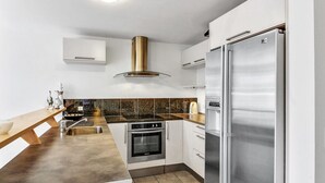 Uma cozinha moderna com geladeira de aço inoxidável, forno embutido e fogão a gás.