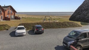 Uma propriedade costeira com casa, entrada de cascalho e vista para a praia.