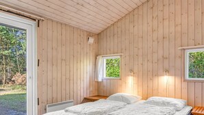 Een slaapkamer met een bed, twee ramen en uitzicht op de omgeving.