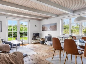 A spacious living area with a fireplace, a television, and a dining table with chairs.
