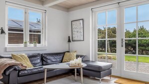 Een moderne woonkamer met een leren bank, een ronde salontafel en een grote schuifdeur naar een buitenruimte.