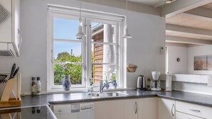 Een moderne keuken met een vaatwasser, dubbele spoelbak en een koffiezetapparaat.