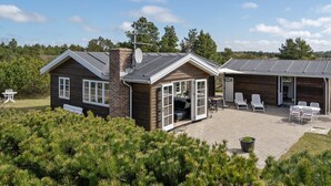 Een chalet met twee verdiepingen, een terras, een schoorsteen en een schotelantenne.