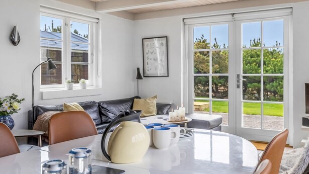 Een moderne woonkamer met een eethoek, grote ramen en uitzicht op het omliggende landschap.