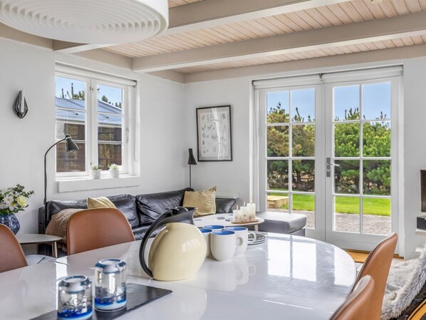 A modern living room with a dining area, large windows, and a view of the outdoors.