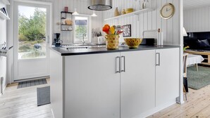 Een moderne keuken met witte kasten, een groot eiland en uitzicht op de omgeving.