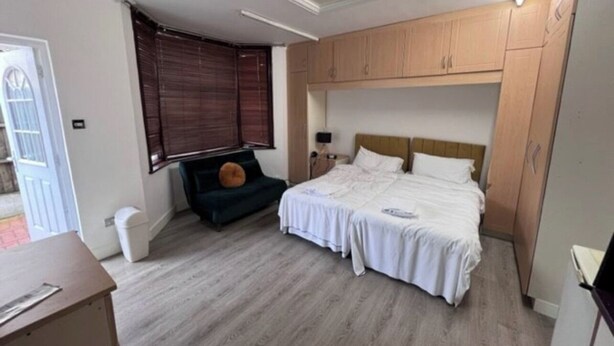A bedroom with two beds, a desk, a chair, and a window with blinds. - Inviting 1-bed Apartment in Ilford (Ilford)