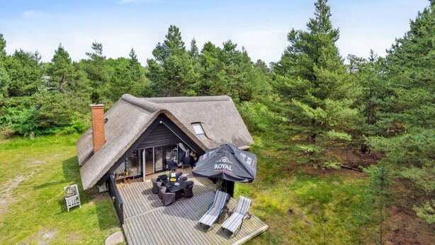 A thatched-roof cabin with a deck, outdoor seating, and a patio umbrella. - "Magga" - 3.2km from the sea by Interhome (Rømø)