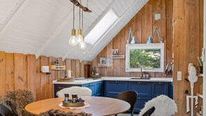 A cozy kitchen with wooden walls, a central island, and a dining area with a round table and chairs. - "Magga" - 3.2km from the sea by Interhome (Rømø)