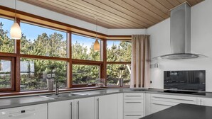 Una cocina moderna con ventanas amplias, horno empotrado y pileta de acero inoxidable.