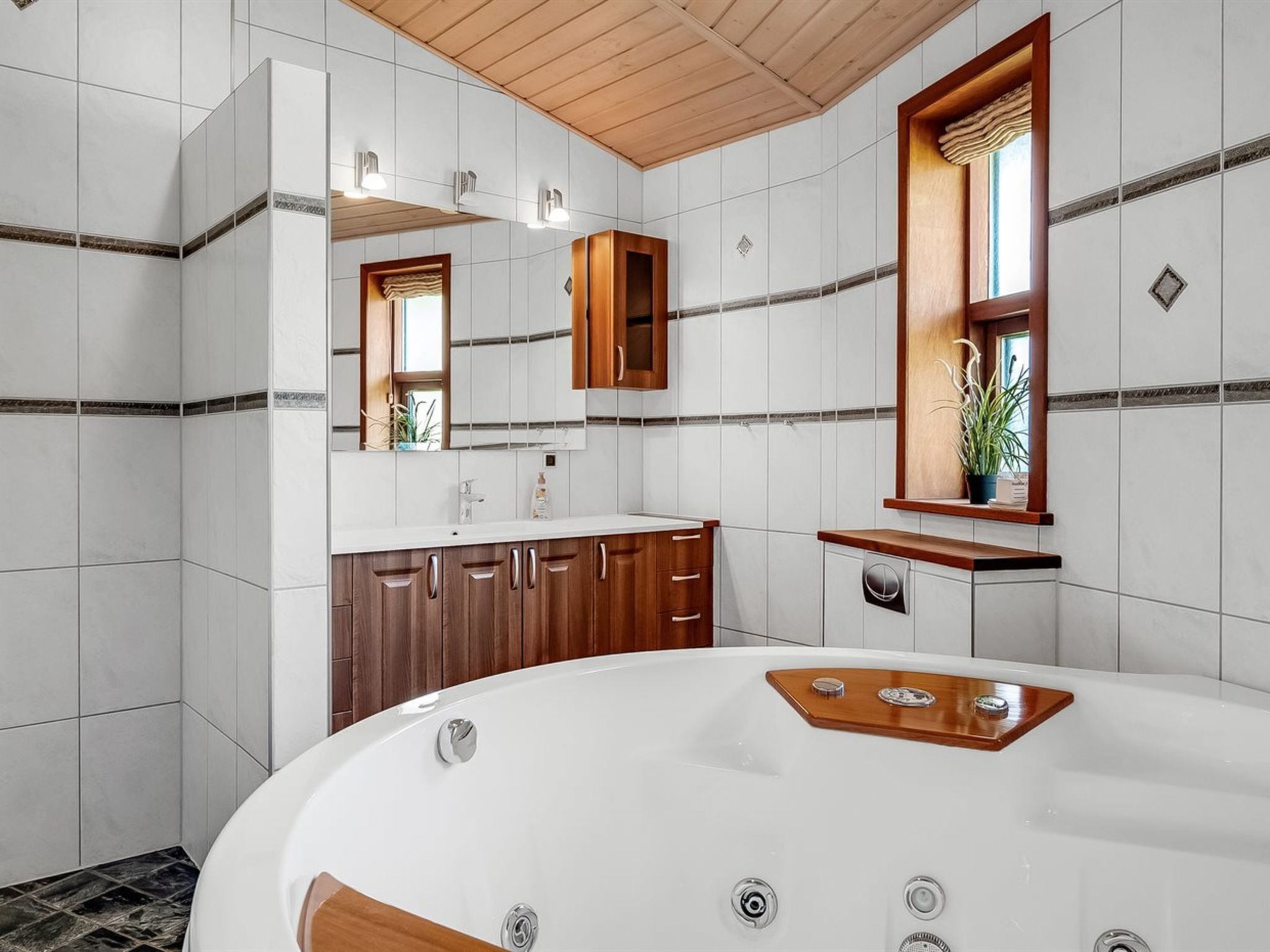 Une salle de bain moderne avec une baignoire sur pieds, des meubles en bois et un grand miroir.