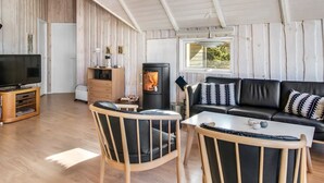 A cozy living room with a TV, wooden furniture, a fireplace, and a window.