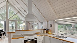 A modern kitchen with white cabinetry, a built-in oven, and a large window offering a view of trees.