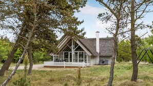 A house with a thatched roof, large windows, and a deck.