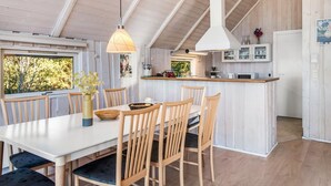 A modern kitchen with white cabinets, a wooden island, and a hanging pendant light.