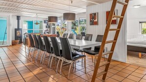 Un comedor amplio con una mesa larga, varias sillas y una escalera de madera.
