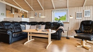 Un salon moderne avec un canapé d’angle en cuir noir, une table basse en bois et un fauteuil en cuir noir.
