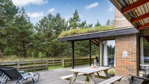 A wooden deck with a picnic table and chairs, a covered seating area, and a brick building with a glass door. - "Falki" - 2.5km from the sea by Interhome (Rømø)