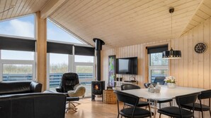 Ein gemütliches Wohnzimmer mit Kamin, Fernseher und einem Essbereich mit Stühlen und Tisch.