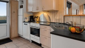 Eine moderne Küche mit weißen Schränken, einer schwarzen Arbeitsplatte und einem Edelstahlspülbecken. Auf der Arbeitsplatte befinden sich ein Herd, ein Backofen und eine Kaffeemaschine.