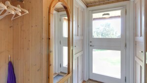 A wooden interior with a white door, a mirror, and a purple towel on a rack.