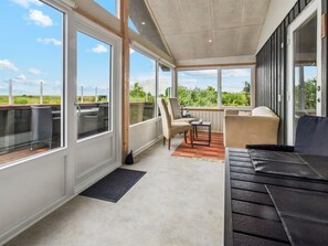 Un espace extérieur aménagé, abrité et doté d’une vue sur la campagne, avec une table et des chaises, ainsi qu’un canapé.