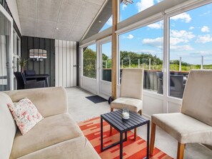 A spacious balcony with a modern design, featuring a sofa set, a small table, and a view of the surrounding landscape.