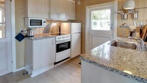 A modern kitchen with wooden cabinets, a granite countertop, stainless steel appliances, and pendant lighting.