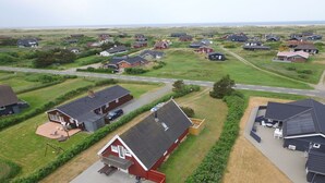A residential area with houses, a road, and a grassy field.