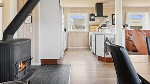 A cozy interior with a wood-burning stove, a kitchen with white cabinets, and a living area with a leather sofa.