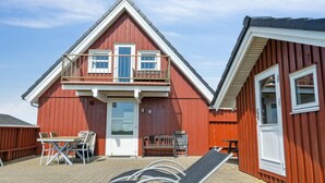 A red wooden building with a balcony, a door, and a small table with chairs.