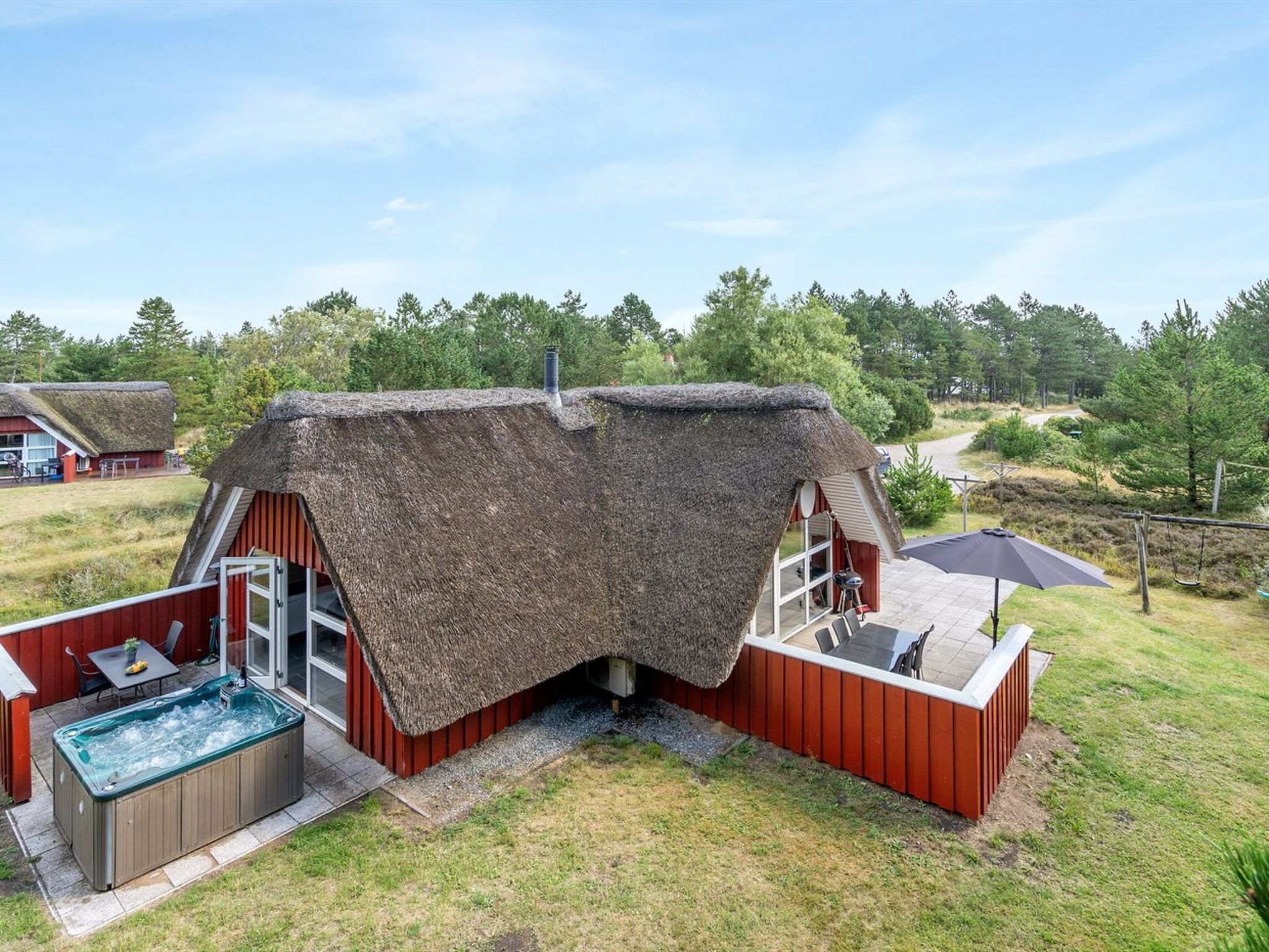 A thatched-roof structure with a hot tub and outdoor seating area.