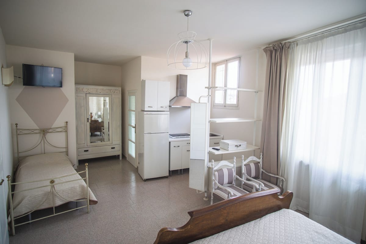 A bedroom with a bed, a desk, a chair, a wardrobe, and a television.