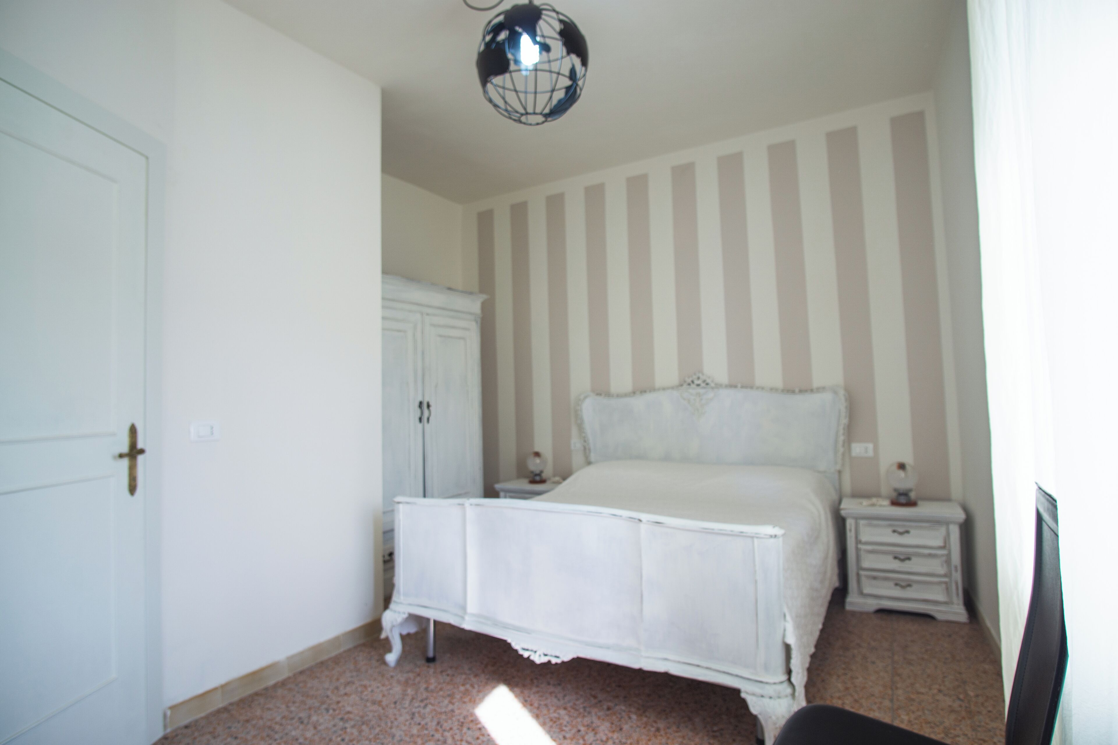 Een slaapkamer met een bed, een kledingkast, een nachtkastje en een lamp in de vorm van een wereldbol.