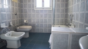 Casa de banho com bidé, sanita e banheira.
