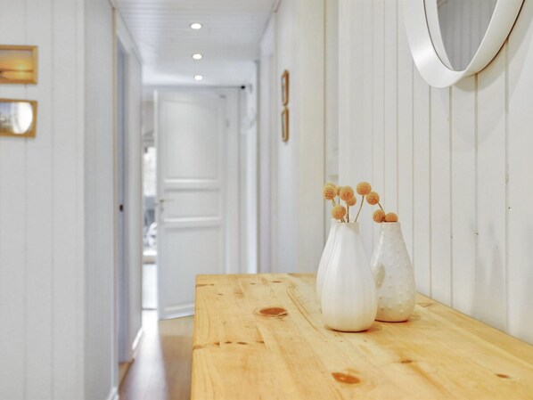 A hallway with a wooden table and white vases with dried flowers.