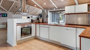 A modern kitchen with white cabinets, a stainless steel range hood, and a wooden countertop. - "Sakulfuer" - 2.5km from the sea by Interhome (Rømø)