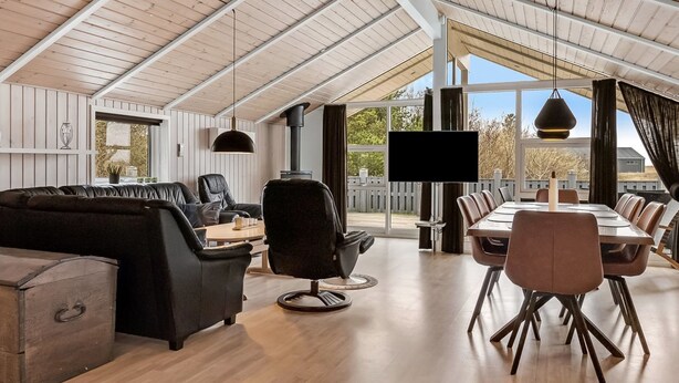 A spacious living area with a high ceiling, a fireplace, a television, and a dining area with a long table and chairs. - "Sakulfuer" - 2.5km from the sea by Interhome (Rømø)