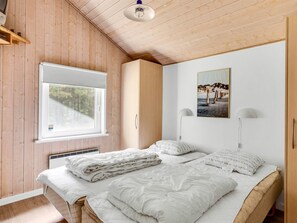 A bedroom with a bed, a window, a wall-mounted picture, and a ceiling light.