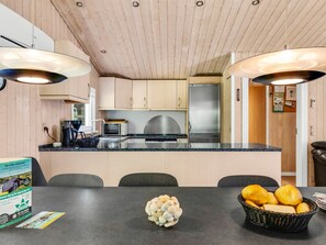 A modern kitchen with wooden cabinets, a stainless steel refrigerator, and a granite countertop.