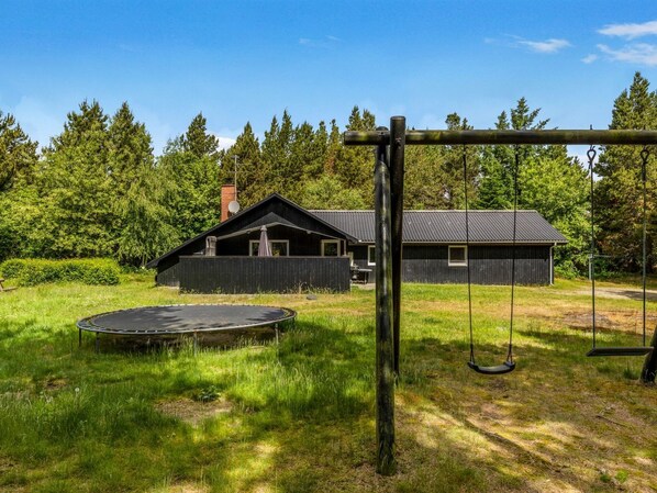 A house with a swing set, trampoline, and a fenced yard.