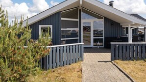 A modern building with a large glass door, a covered patio area, and a wooden fence. - "Freek" - 400m from the sea by Interhome (Rømø)
