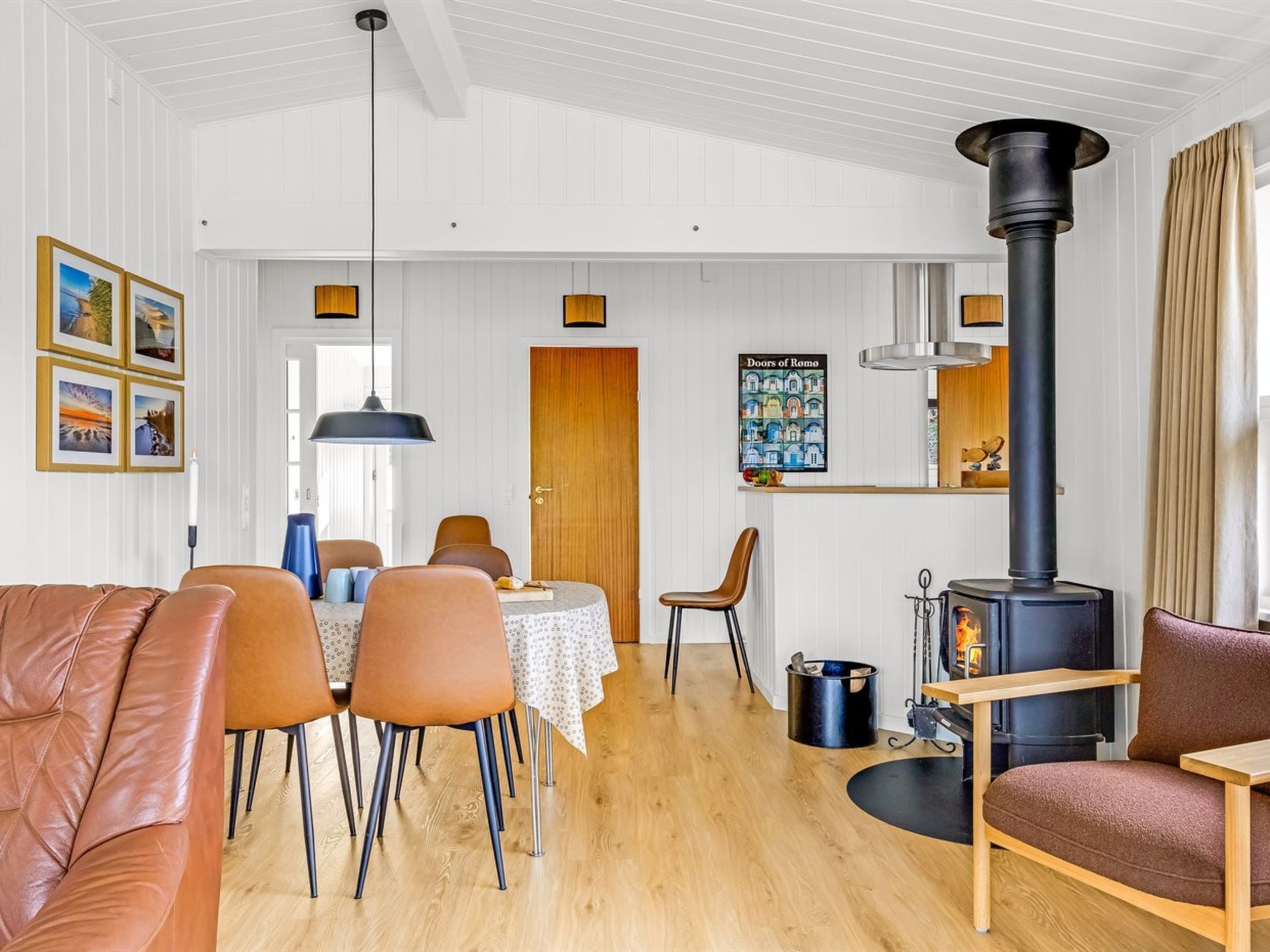 Un salon moderne comprenant un coin repas, un poêle à bois noir et un espace cuisine avec une étagère en bois.
