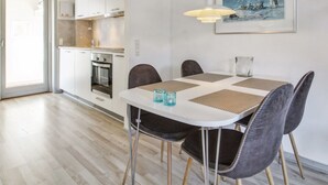 A modern kitchen with white cabinets, a built-in oven, and a dining area with a white table and chairs. - "Arna" - 2.3km from the sea by Interhome (Rømø)