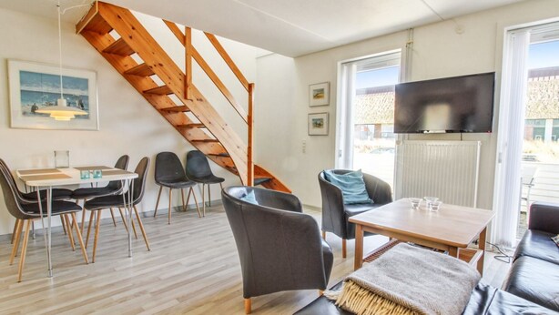 A modern living room with a wooden staircase, a dining area, and a TV. - "Arna" - 2.3km from the sea by Interhome (Rømø)